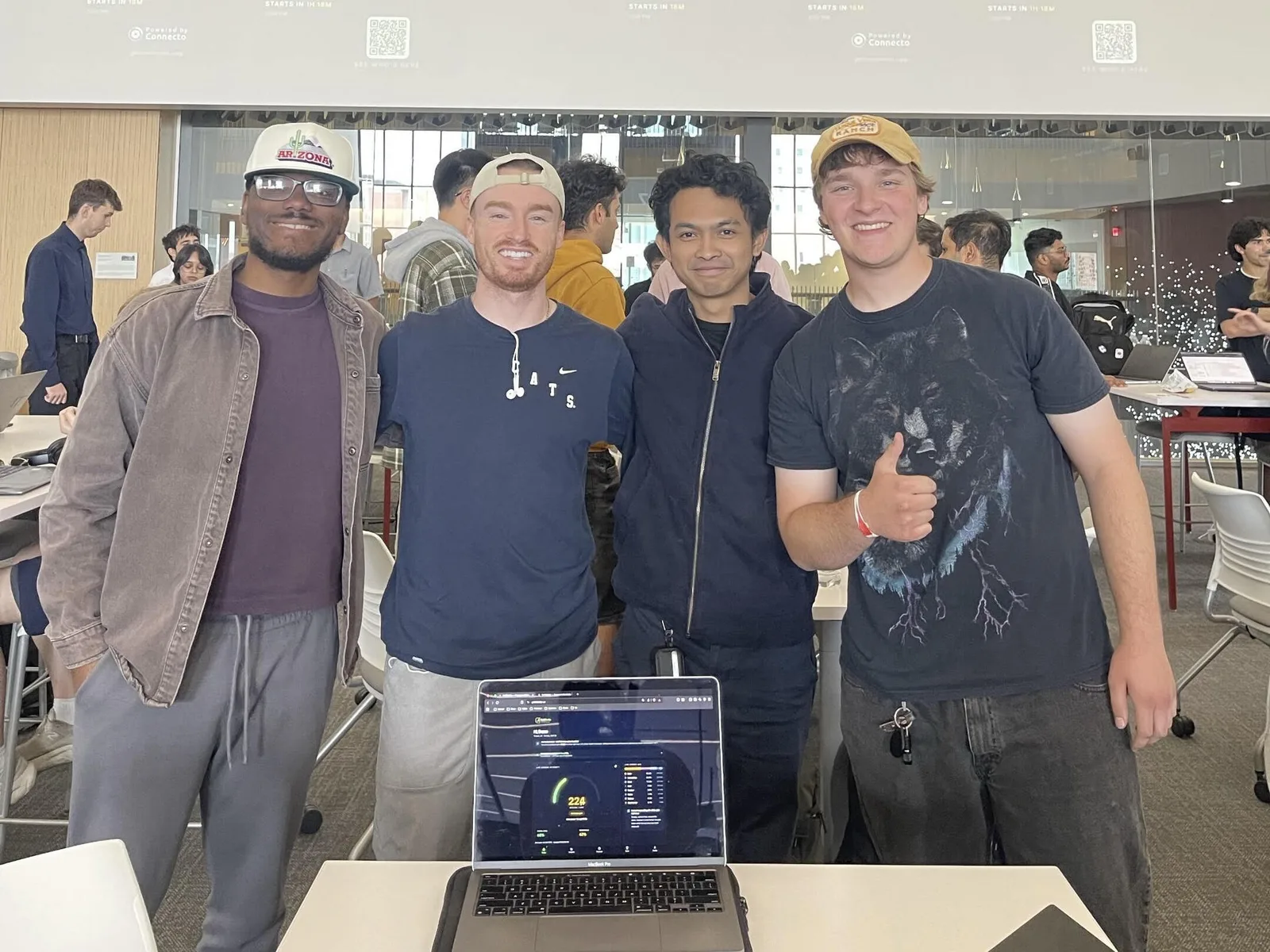 Four GridWise teammates stand behind their project laptop at Hack Arizona